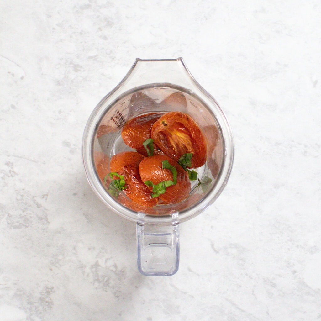 Small blender sitting on my kitchen counter with roasted tomato and basil inside.