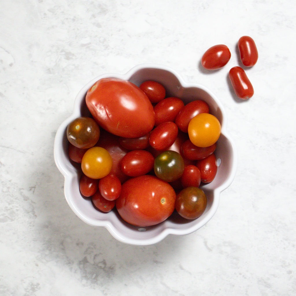 White bowl sitting on my kitchen counter with various tomatoes inside.