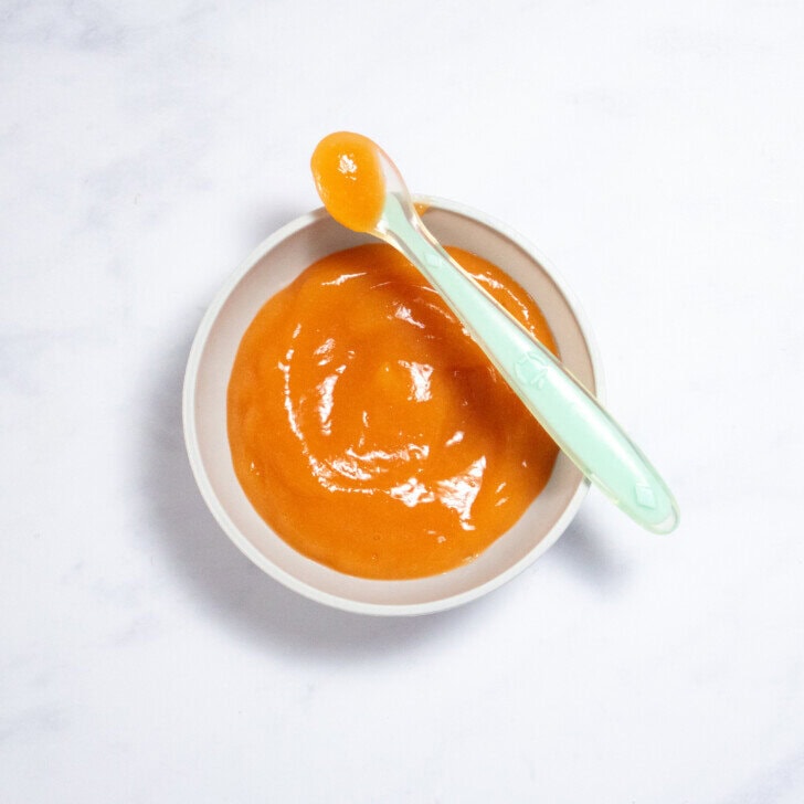 A gray baby bowl on a counter with a smooth papaya baby puree.
