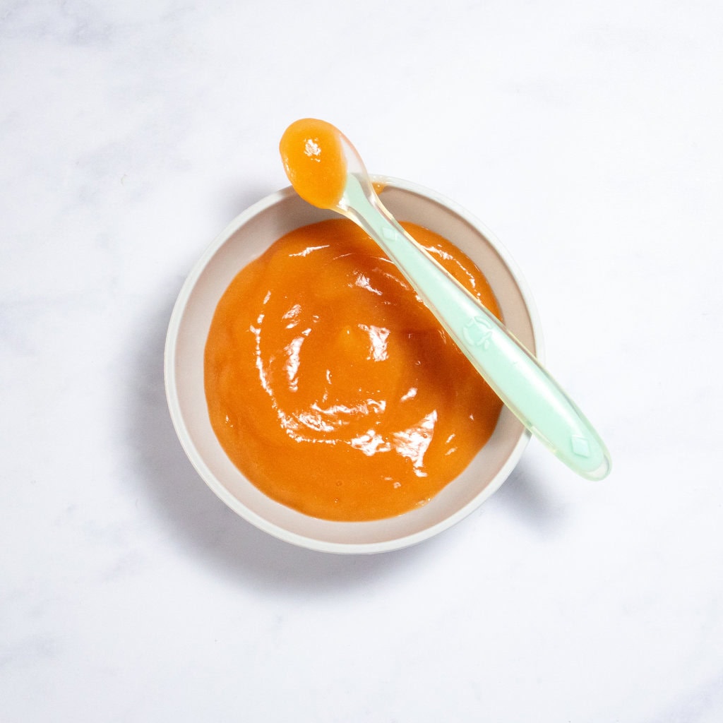 A gray baby bowl on a counter with a smooth papaya baby puree.