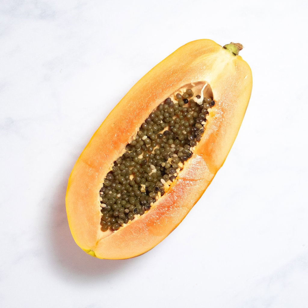 A papaya sitting on my white kitchen counter.
