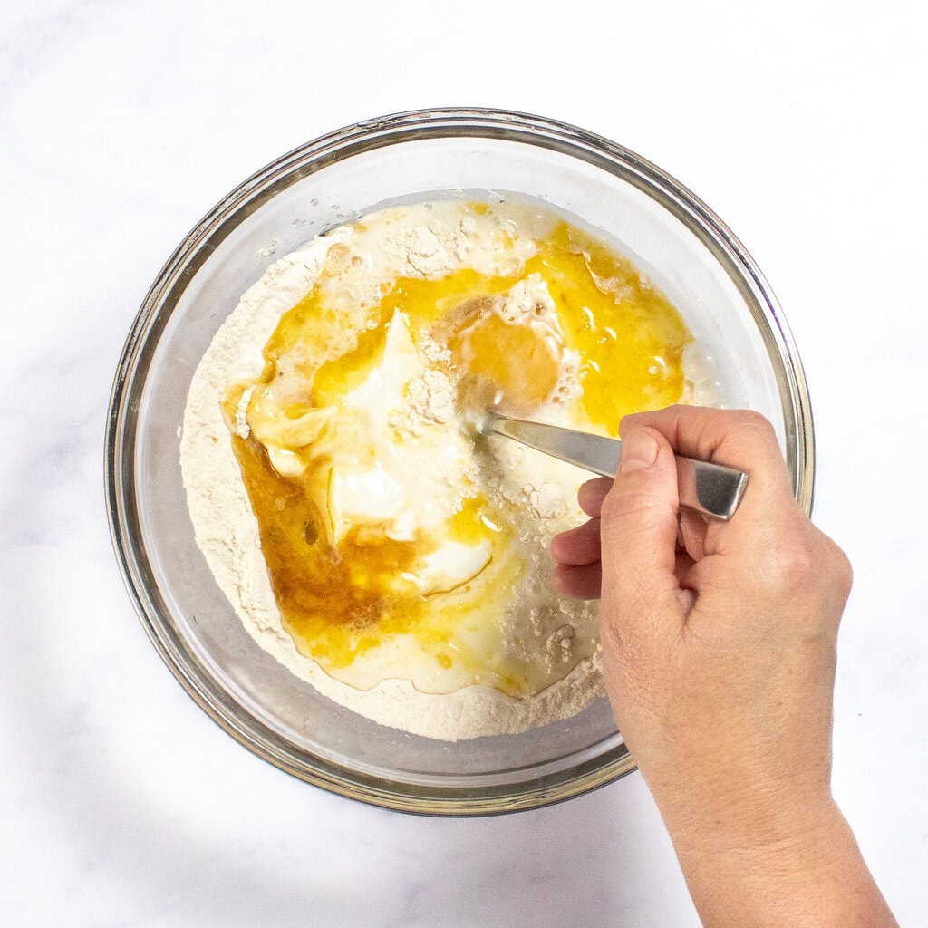 My hand is mixing together the wet and dry ingredients.