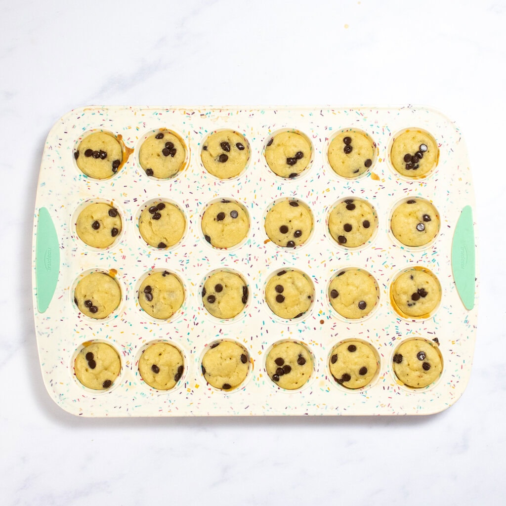 A mini muffin tray sitting on my white marble counter with golden brown mini pancake bites inside.
